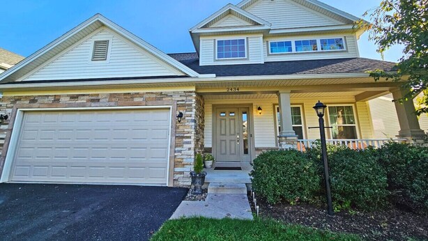 A two-story house with a garage, a front porch, and a well-maintained lawn.