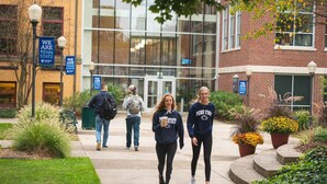A group of people walking on a campus pathway with signs indicating 'We Are Penn State'.