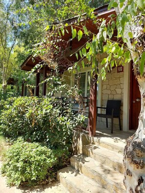 A stone building with a wooden porch, a bench, and a staircase leading to the entrance.