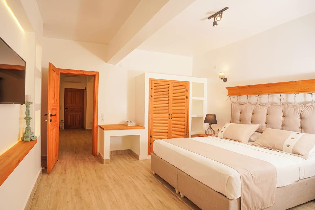 A bedroom with a bed, bedside table, wardrobe, and a TV on the wall.