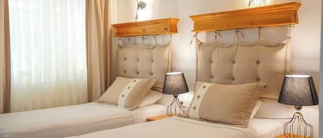 A double room with two beds, each with a wooden headboard and matching lamps.