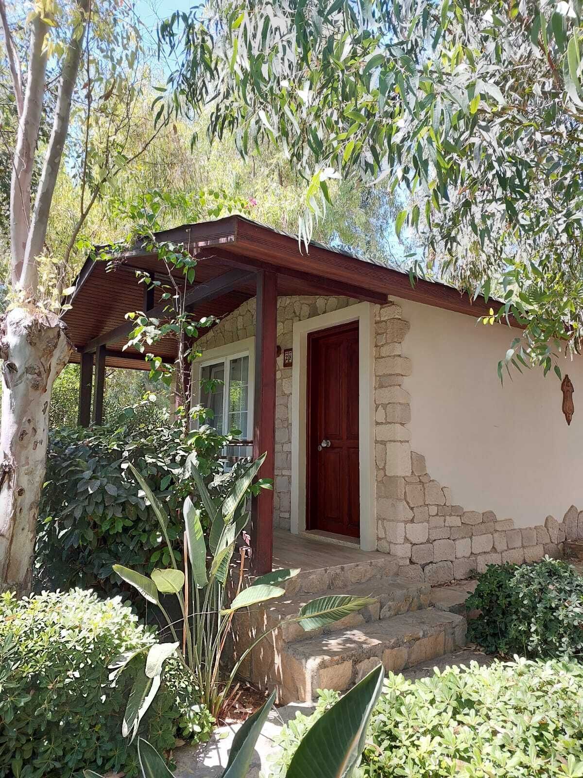 A rustic stone building with a wooden porch and a red door.