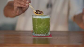 A person holding a cocktail with a lemon slice garnish.