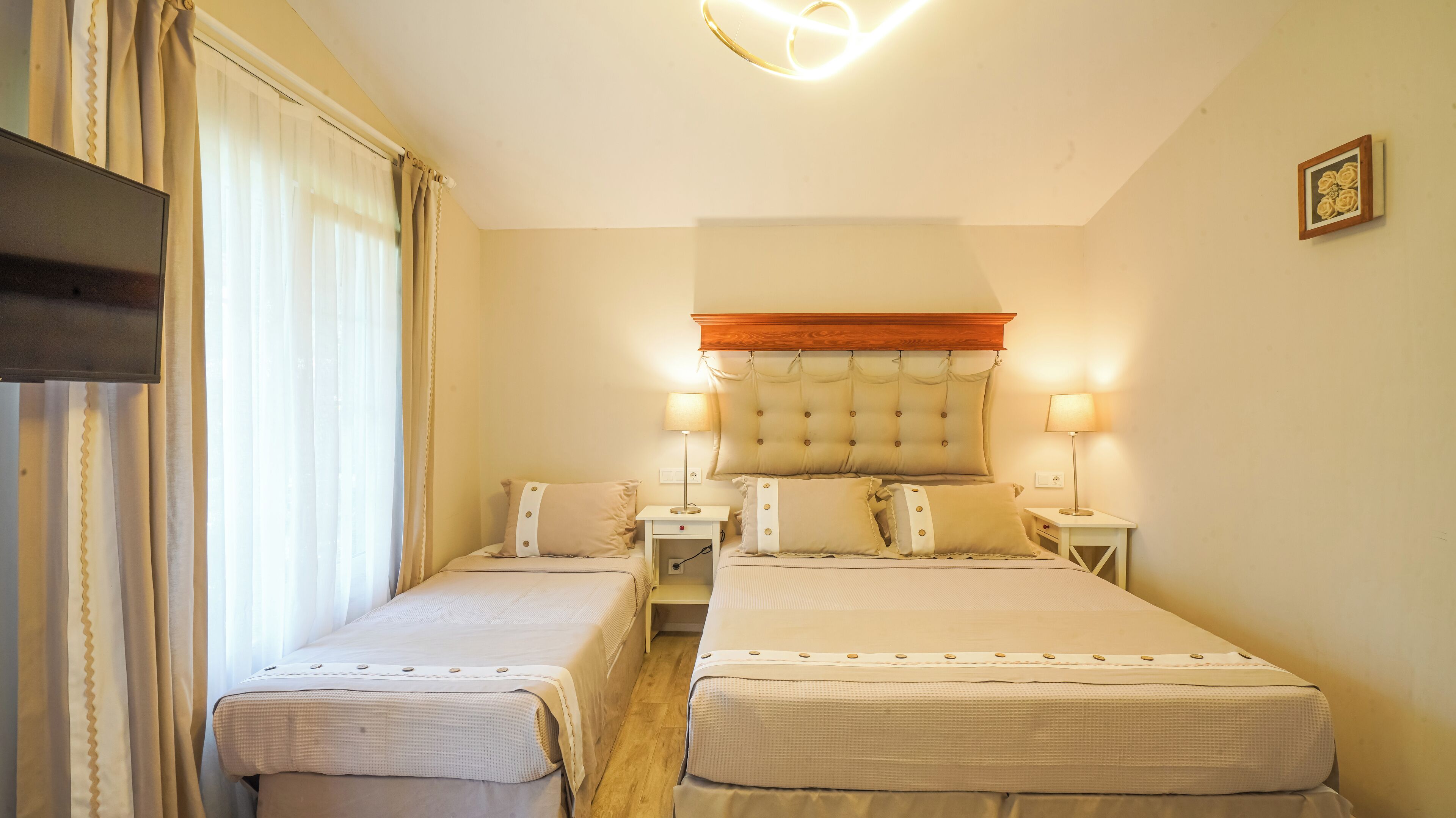 A hotel room with two beds, a wooden headboard, bedside lamps, and a small table.