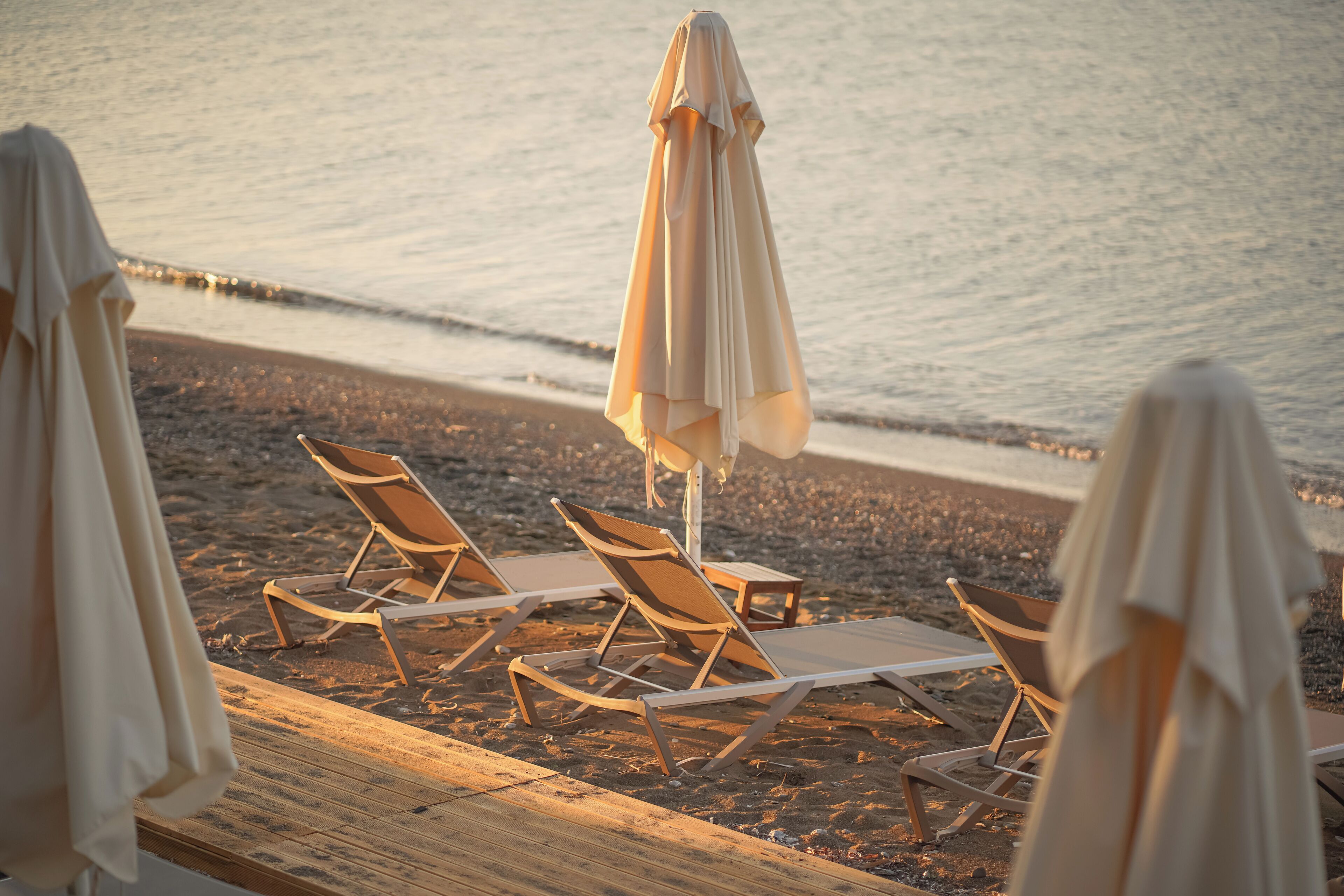 A beachside setting with lounge chairs and umbrellas on a wooden deck.