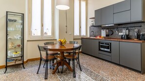Una cocina con una mesa de comedor, sillas, un frutero y un armario.