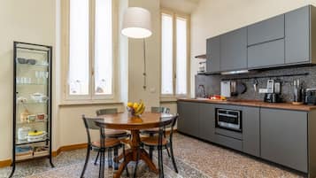Eine Küche mit Esstisch, Stühlen, Obstschale und Schrank.