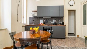 Una cocina moderna con armarios grises, una mesa de comedor de madera y un frutero.