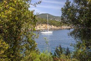 Ein Boot auf ruhigem Wasser, umgeben von Grün und Hügeln.