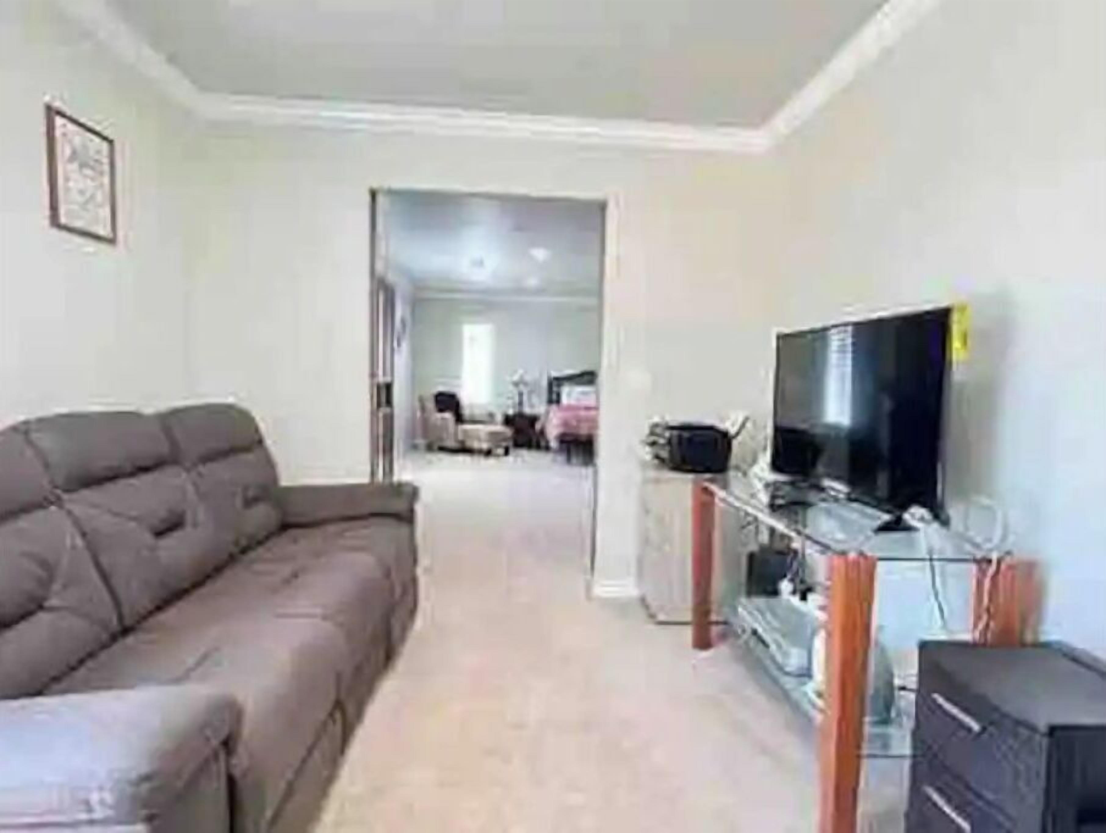 Una sala de estar con un sofá, un televisor y un mueble.