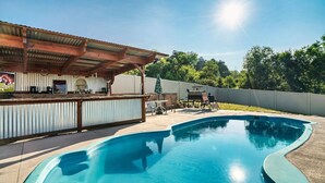 Ein Pool mit gewölbter Kante, eine überdachte Bar und Sitzgelegenheiten im Freien.
