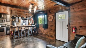 Ein rustikales Blockhaus-Interieur mit Küche, Bar und Sitzgelegenheiten.