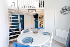 Enjoy meals in this stylish dining area with a round table for four, featuring a TV above and a staircase leading to the upper level.