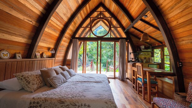 Een knus slaapkamer in een houten chalet, met een groot bed, een bureau en uitzicht op de natuur.