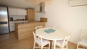 Une cuisine moderne avec des meubles blancs, un îlot central en bois et une table de salle à manger ronde, assortie de chaises blanches.