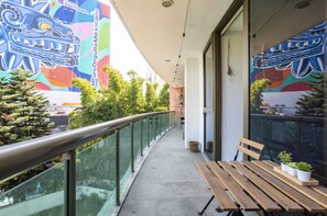 Enjoy the serene views of the vibrant mural and lush greenery from this outdoor balcony.