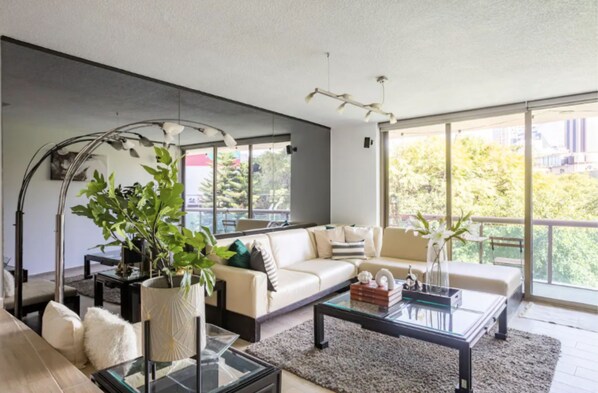 Relax in this stylish living room with a sofa set, floor lamp, and large window offering a view of the outdoors.