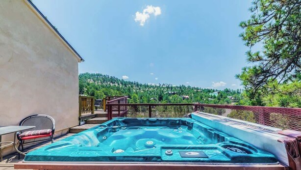 A hot tub on a deck with a view of a forested hill.