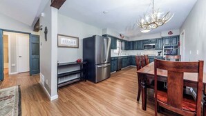 A modern kitchen with dark cabinets, stainless steel appliances, and a wooden dining table.