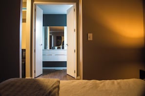 Comfortable accommodations feature a bed, a doorway to a bathroom with a mirror and sink.