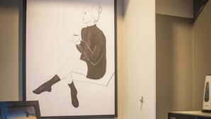 Ein Zimmer mit einem gerahmten Kunstwerk, einem Regal mit Gläsern und einer Mikrowelle.