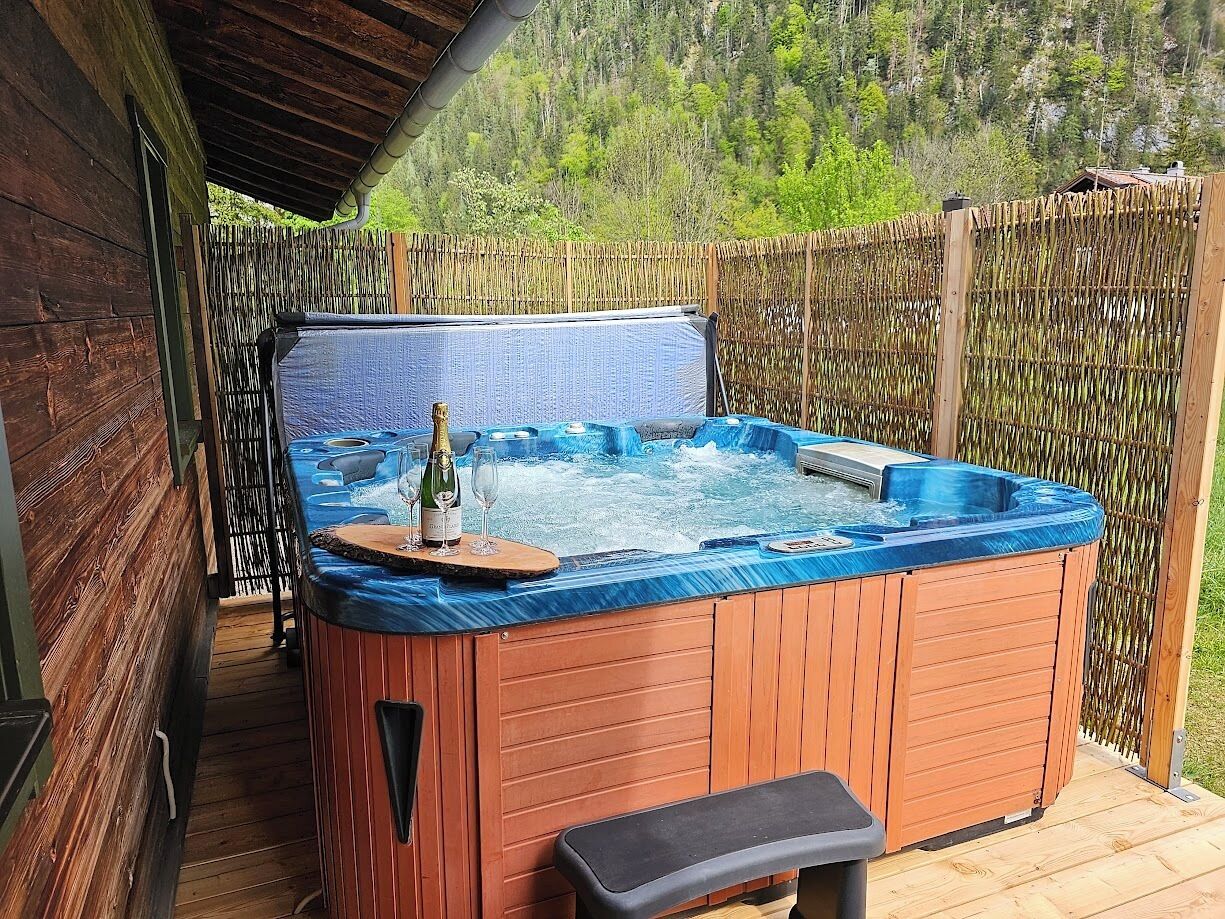 A hot tub with a wooden exterior, a wooden deck, and a bamboo fence.