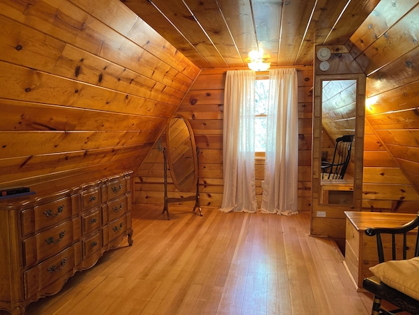Une pièce aux murs lambrés, avec une commode, une chaise et un miroir.