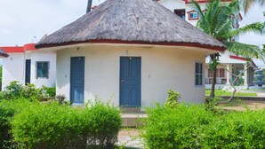 A small, single-story building with a thatched roof and a blue door.