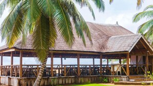 A thatched-roof structure with wooden railings, likely a beachside building or restaurant.