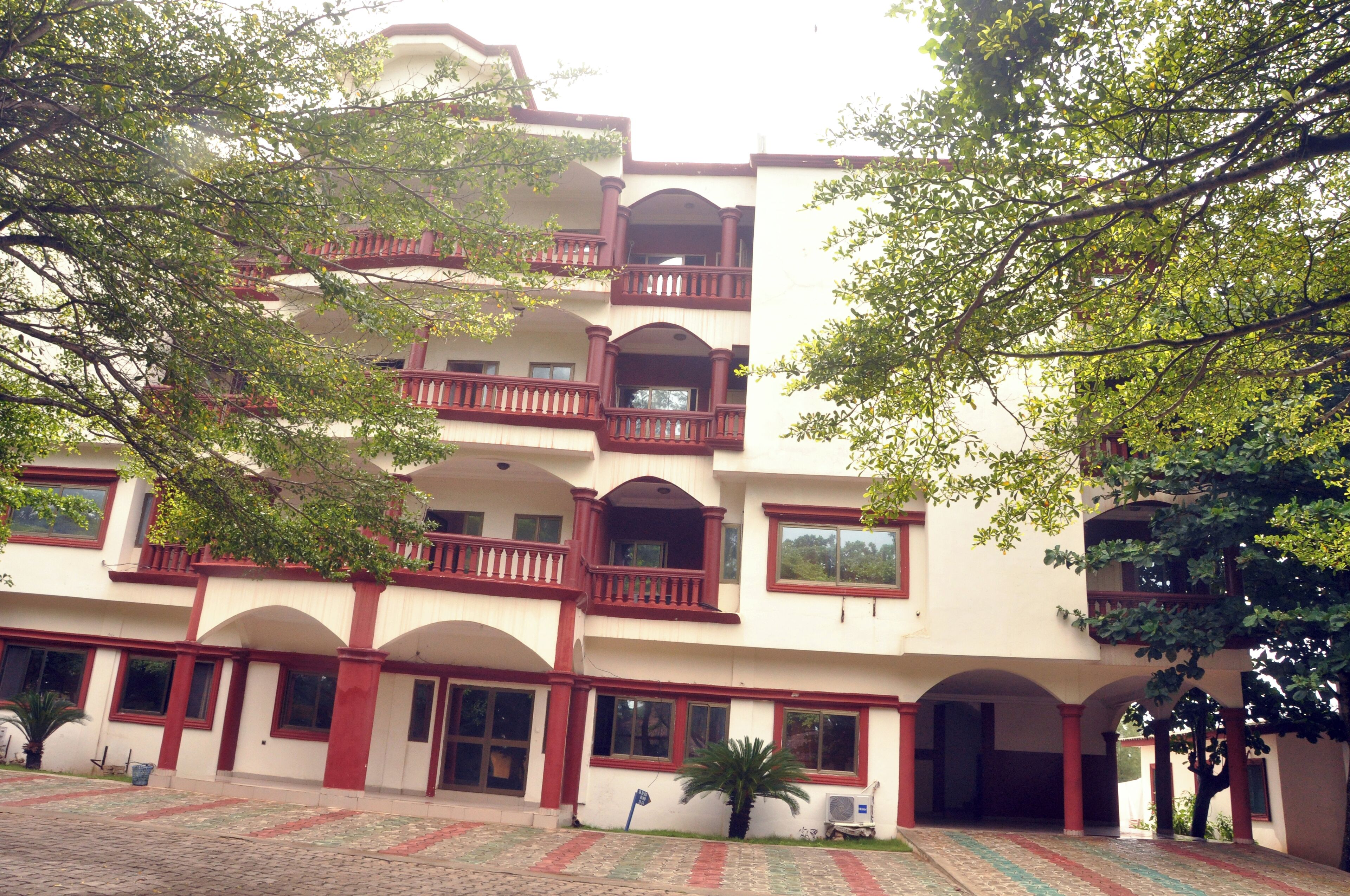 A multi-story building with balconies, arched windows, and a courtyard with patterned paving.