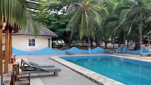 A swimming pool with lounge chairs and palm trees.