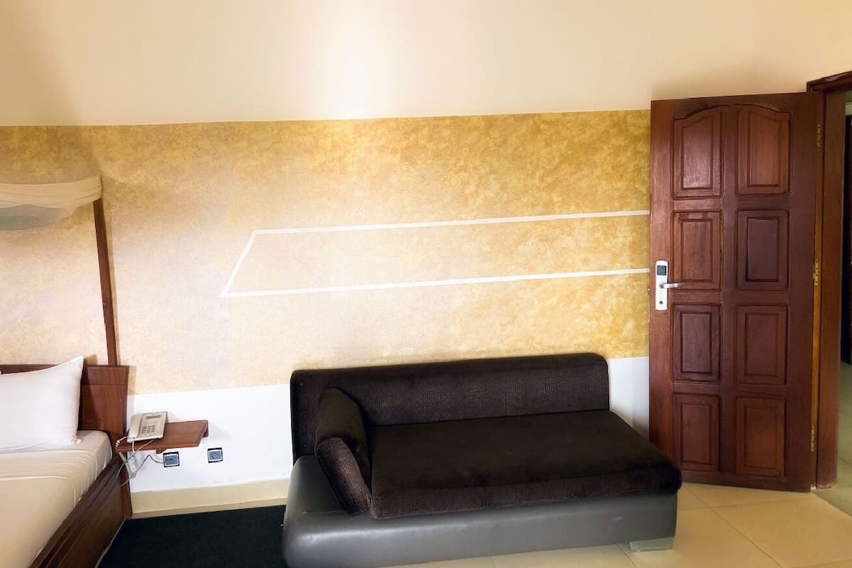 Habitació d'hotel amb llit, sofà, telèfon fixat a la paret i una porta.
