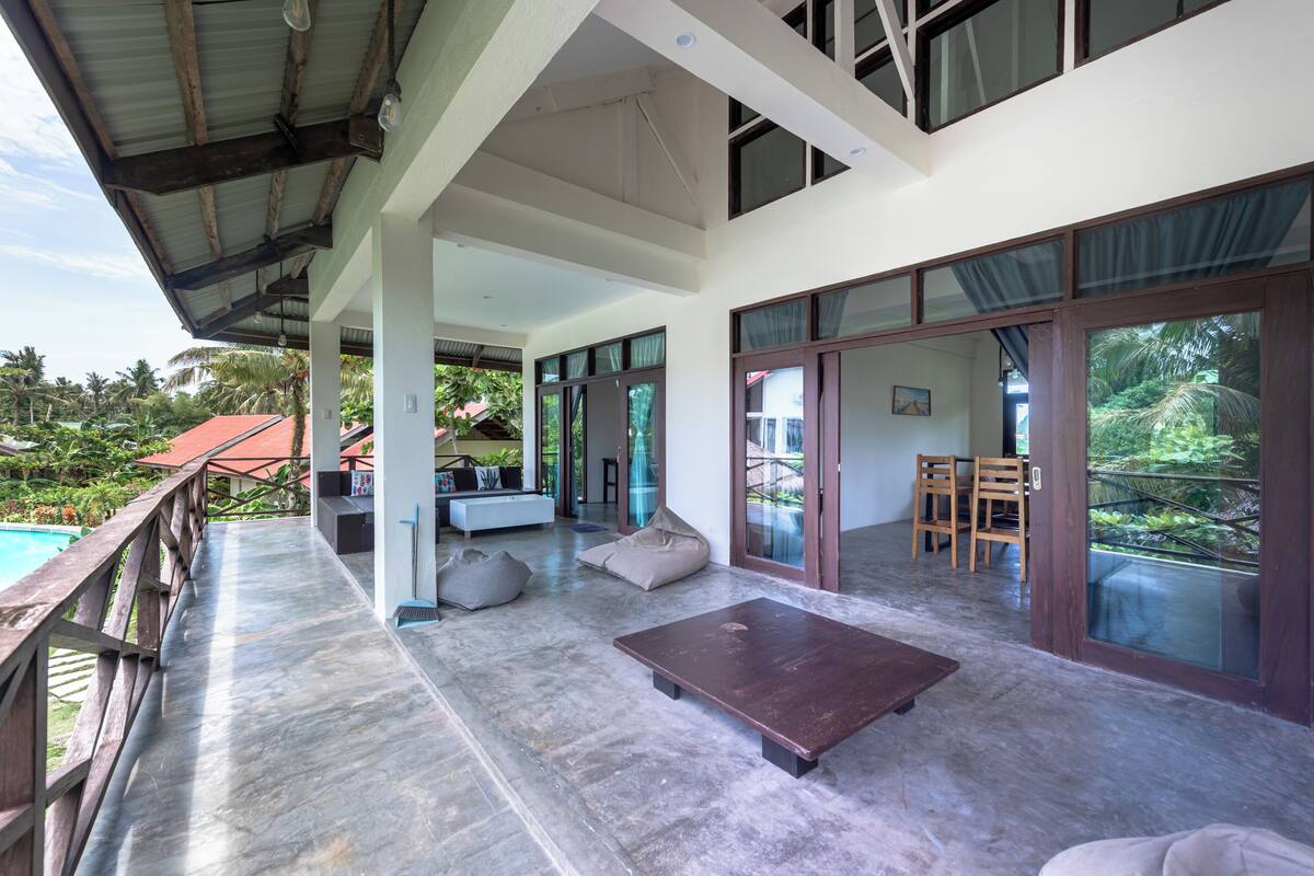 A spacious living area with a pool, large windows, and a wooden deck.