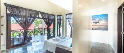 A spacious bedroom with a large bed, a balcony with curtains, and a painting of a seascape.
