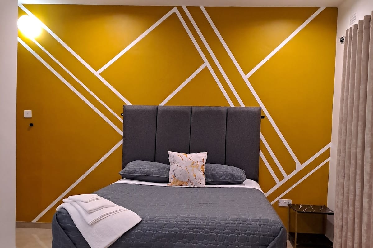 A modern bedroom with a bed, a nightstand, and a chair.