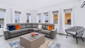 A modern living room with a grey sectional sofa, a round coffee table, and a grey armchair.