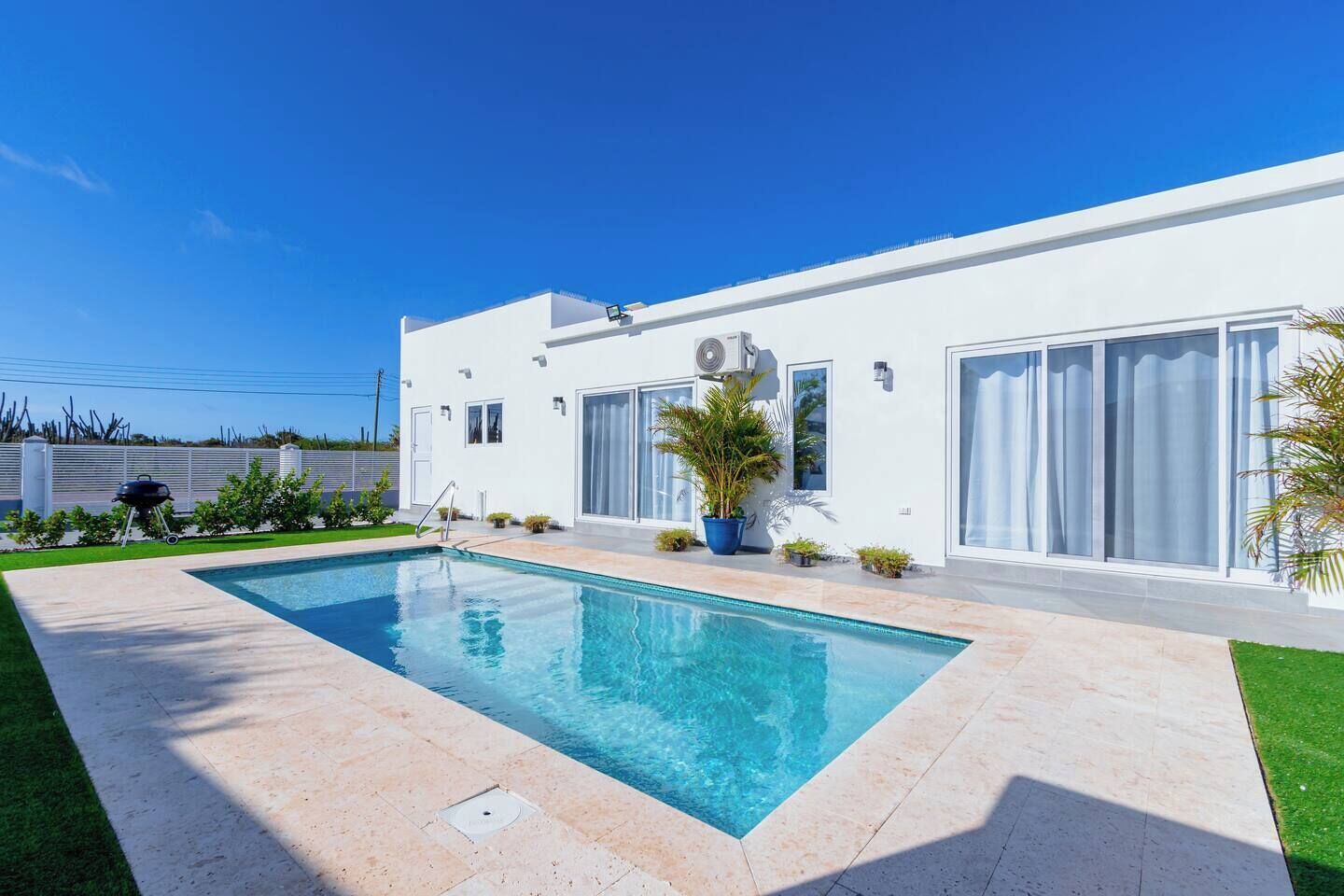 Una casa moderna con piscina, ventanas amplias y césped cuidado.