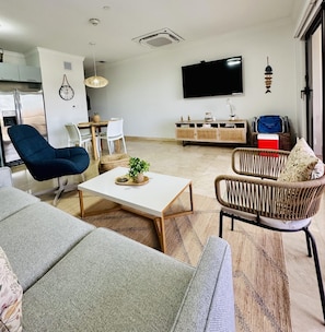 Una sala de estar moderna con un sofá, un sillón, una mesa de centro y un televisor montado en la pared.