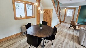Ruokailutila, jossa on pyöreä pöytä, tuolit ja katosta roikkuvat riippuvalaisimet.