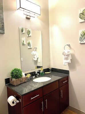 A bathroom with a sink, mirror, and two towel racks. There are decorative plants and toiletries on the counter.
