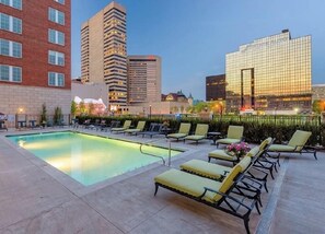 A rooftop pool area with lounge chairs and a view of surrounding buildings.