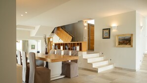Un interior moderno con zona de comedor, escalera y obras de arte.