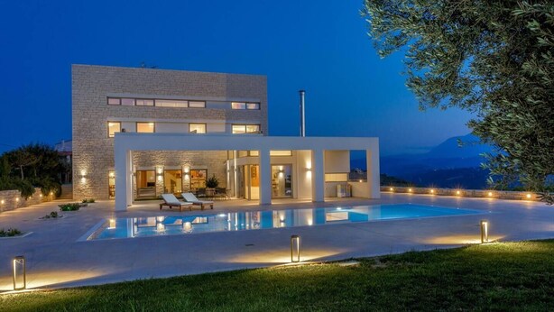 Una casa moderna con piscina, mobiliario exterior y vistas a la montaña.