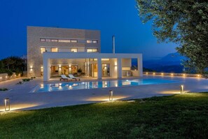 Ein modernes Haus mit Swimmingpool, Sitzgelegenheiten im Freien und Blick auf die Berge.