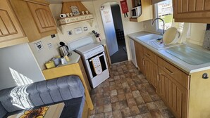 A compact kitchen with wooden cabinets, a stove, a sink, and a refrigerator.