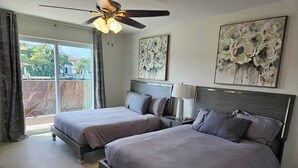 Une chambre avec deux lits, un ventilateur de plafond et des œuvres d’art accrochées aux murs.