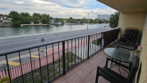Un balcon donnant sur une rivière, une route et des bâtiments situés au loin.