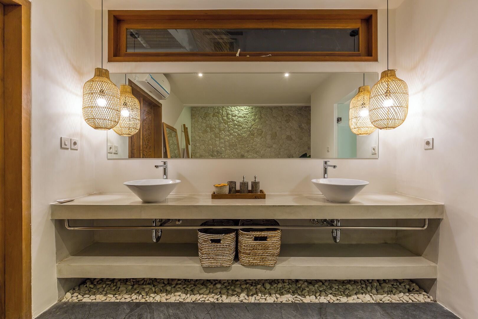 Une salle de bain avec deux lavabos, un grand miroir et des lampes en osier.