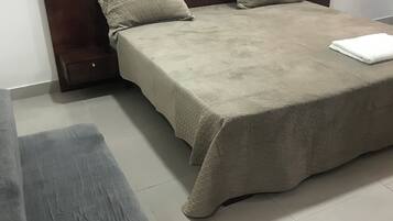 Quarto bem arrumado com cama grande, duas almofadas, mesa de cabeceira e cadeira de madeira.