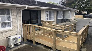 Una edificación de un solo piso con terraza de madera y zona de estar al aire libre techada.